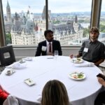 Photo taken during the Together25Ensemble conference featuring several people seated at a round table with white table cloth